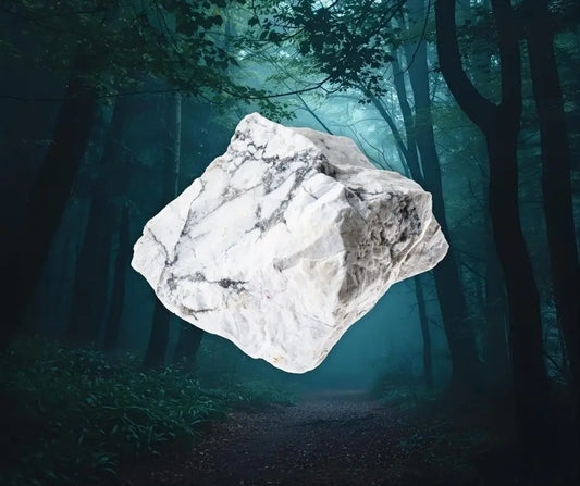 Pierre brute de howlite blanche veinée de gris sur fond de forêt brumeuse, symbole d’apaisement, de patience et de libération émotionnelle – Aura Cristal