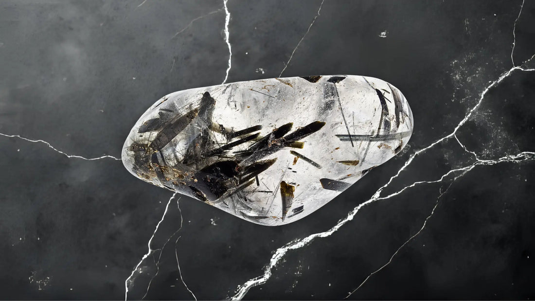 Pierre de quartz tourmaliné transparente avec inclusions noires sur fond minéral, symbole de protection, d’ancrage et d’équilibre énergétique – Aura Cristal